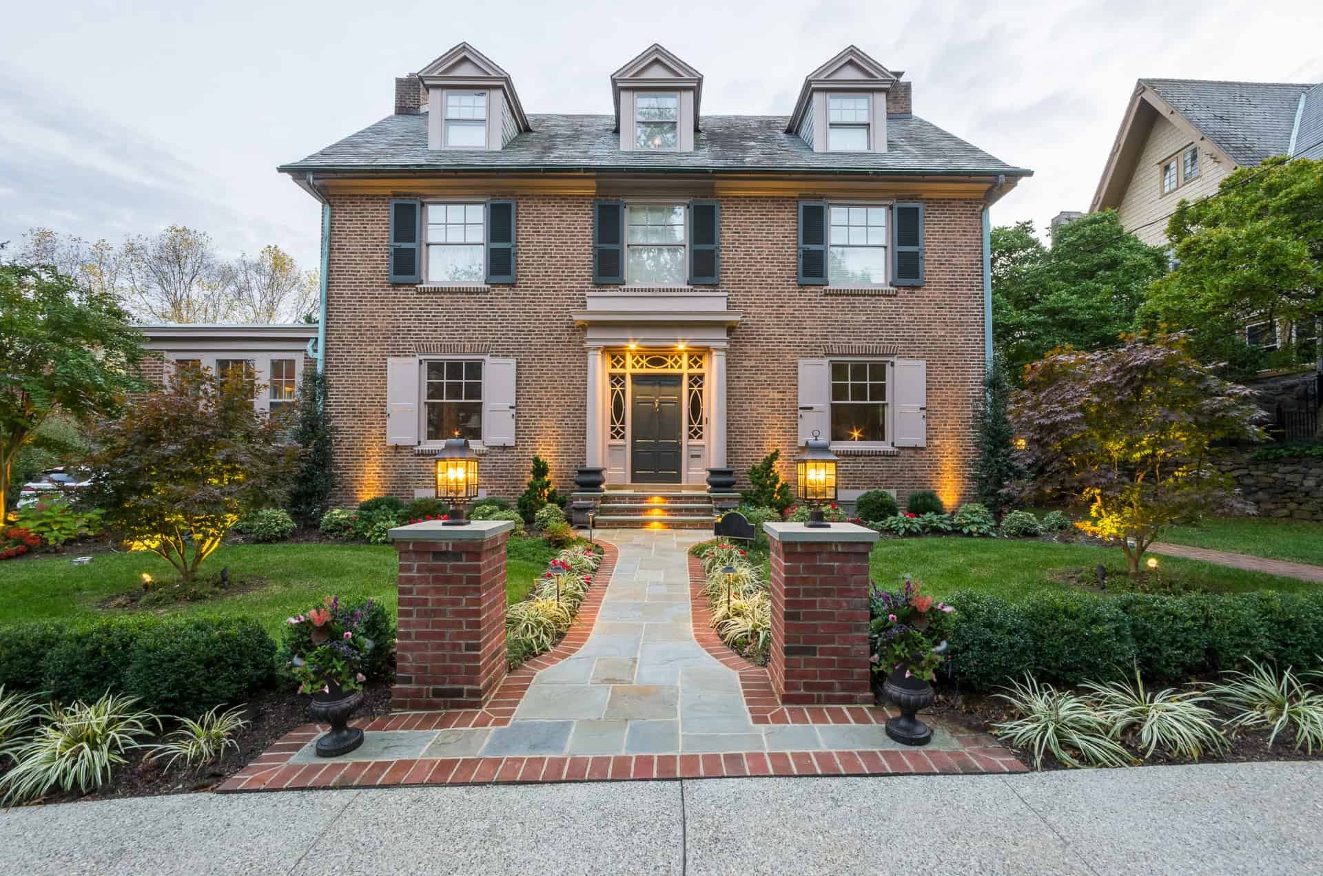Brick home with lit entry, stone walkway, and landscaped front yard in Delaware County, PA