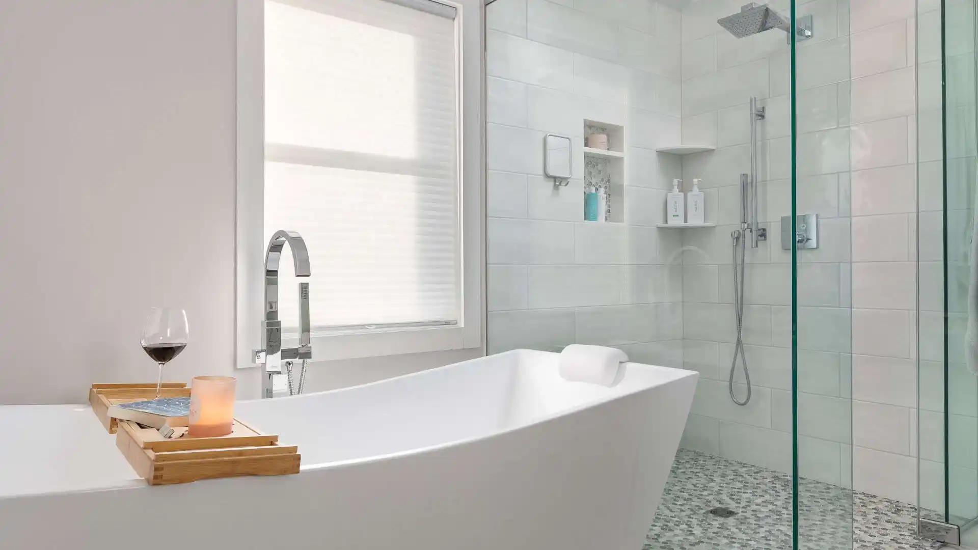 Modern bathroom with a freestanding bathtub featuring a bamboo tray holding a lit candle, glass of red wine, and book. Adjacent is a sleek, glass-enclosed shower. Complementing your indoor oasis, explore outdoor living in Delaware County PA for a complete at-home retreat experience.