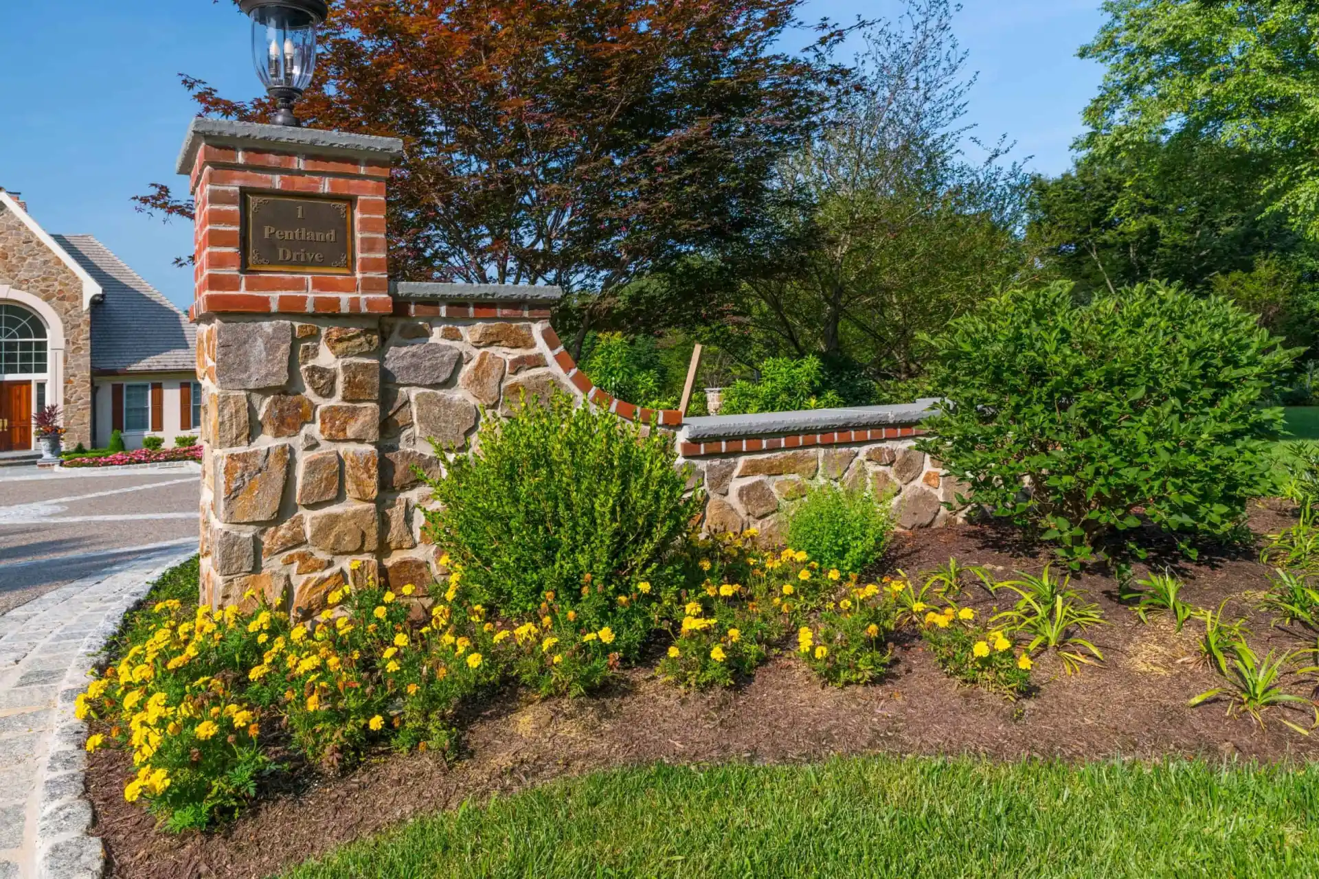 A stone and brick entrance pillar with a sign reading