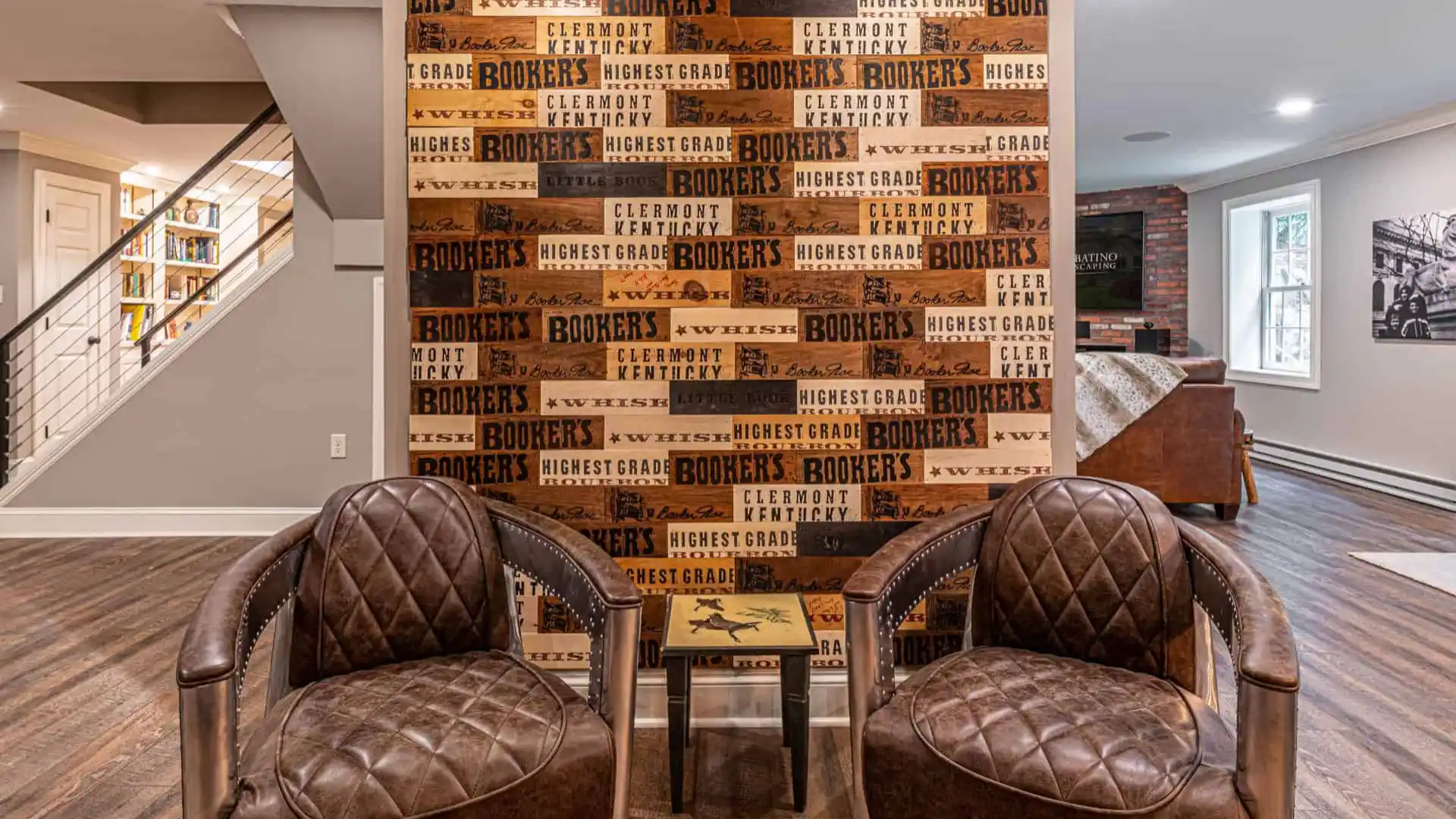 Two brown leather armchairs face a wall adorned with a collage of wooden boards featuring text like 