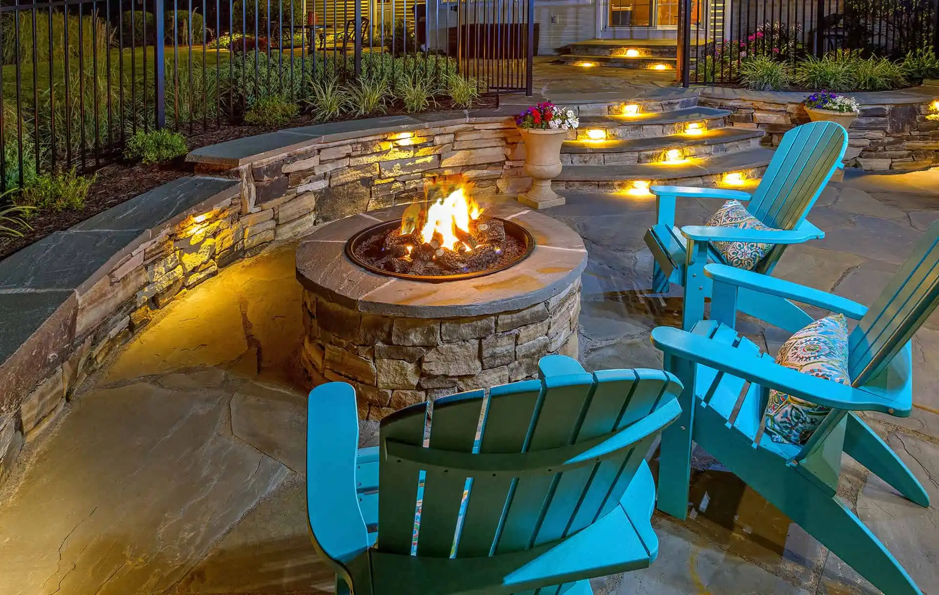 A cozy fire pit surrounded by blue chairs in a well-maintained backyard, perfect for outdoor gatherings.
