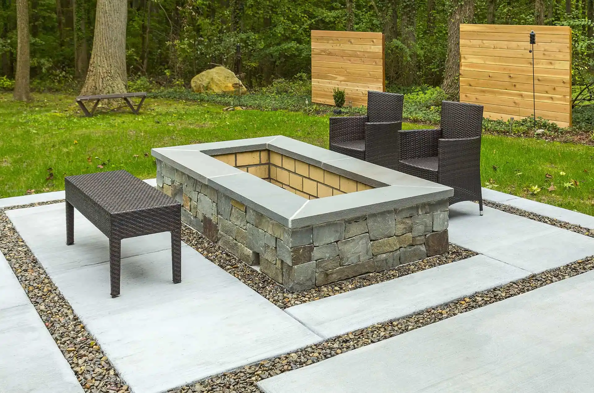 A stone fire pit surrounded by a bench in a cozy backyard setting.