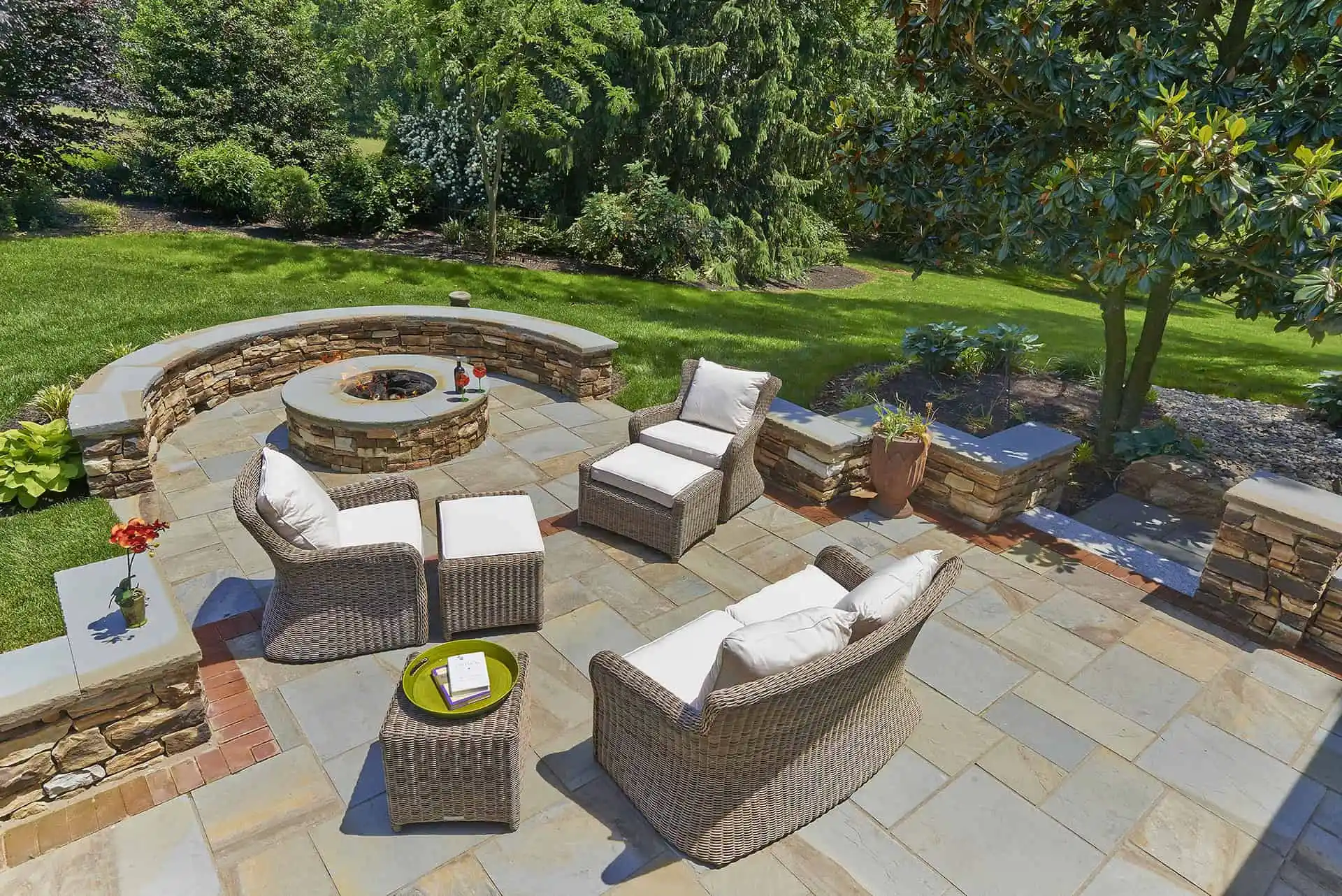 A cozy patio featuring wicker furniture arranged around a central fire pit, ideal for outdoor gatherings.