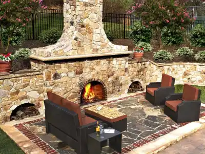 A cozy outdoor patio in Delaware County, PA, features a stone fireplace with four cushioned chairs around a table. The roaring fire adds warmth, while potted plants and shrubs enhance the charm. Ideal for enjoying outdoor living, thanks to expert hardscaping services in the area.